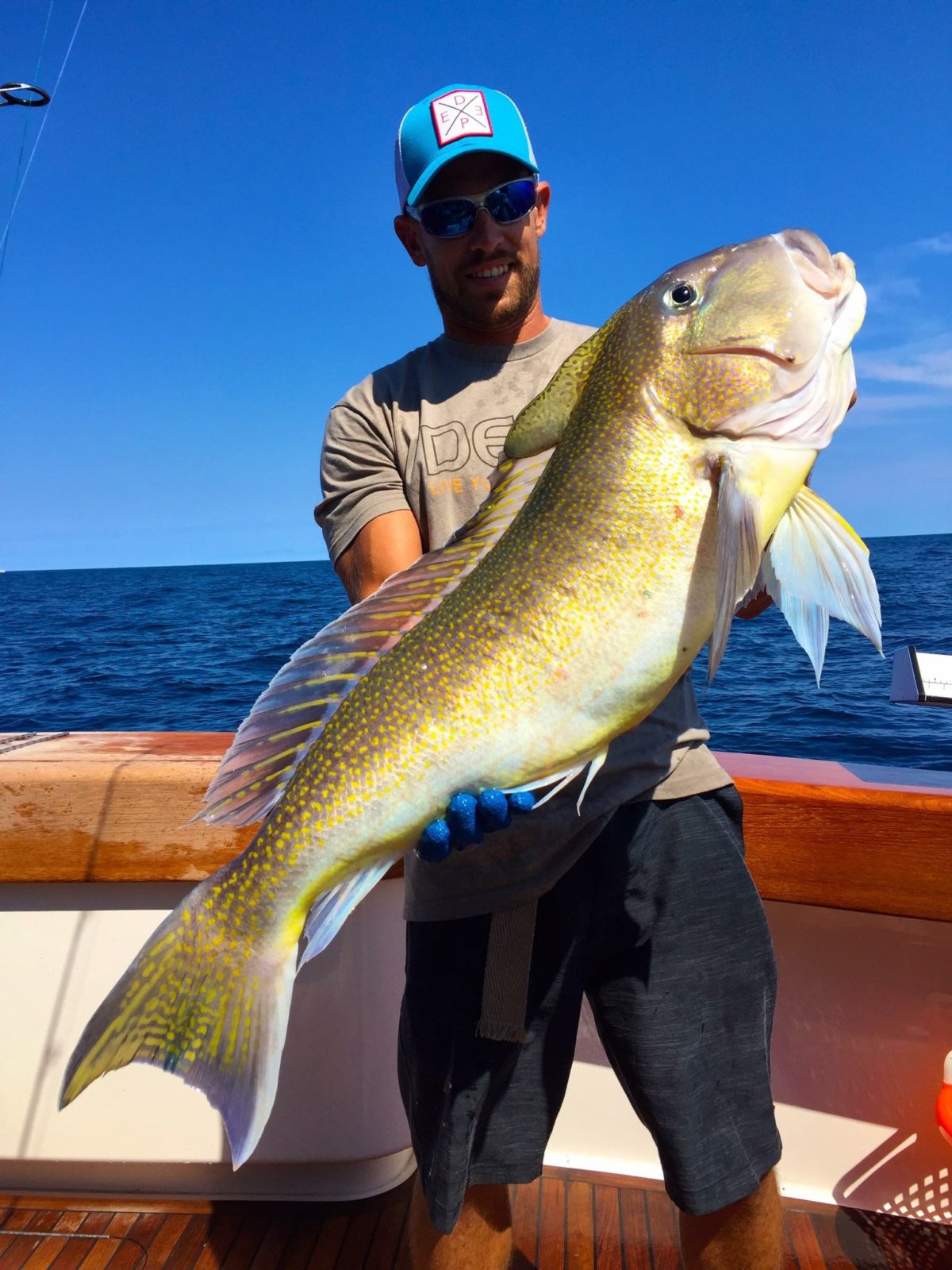 A man holding a fish on top of a boat.