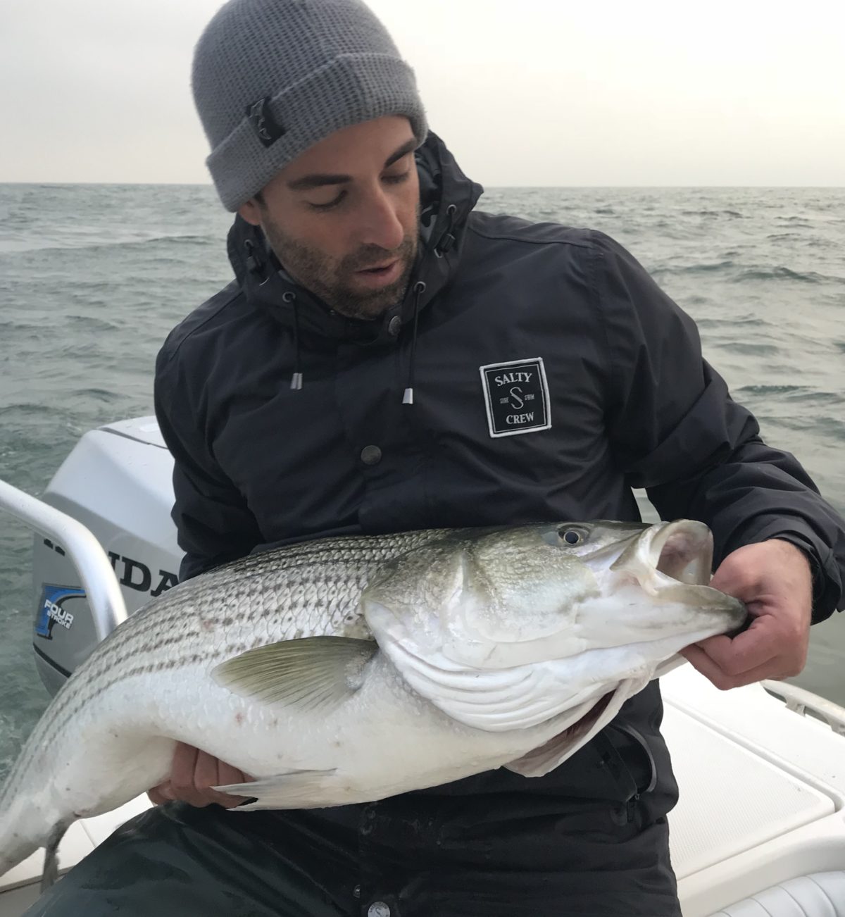 A man holding a fish on top of a boat.