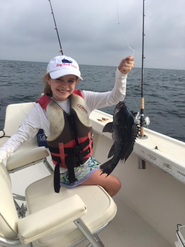 A girl holding a fish while sitting on the boat.