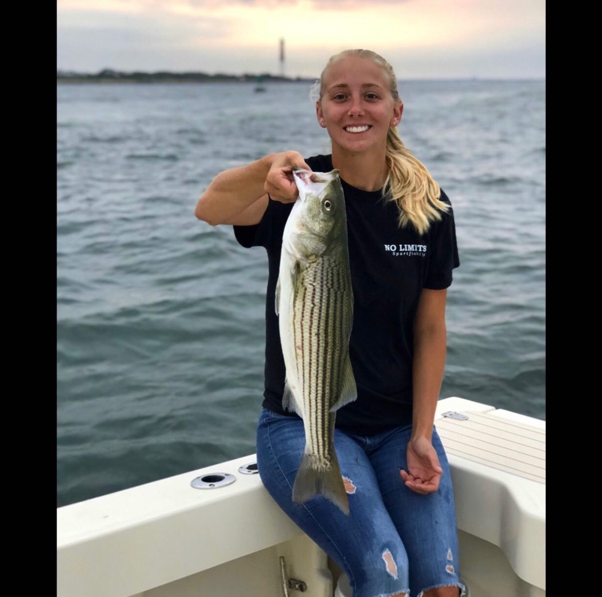 A woman holding a fish on top of a boat.