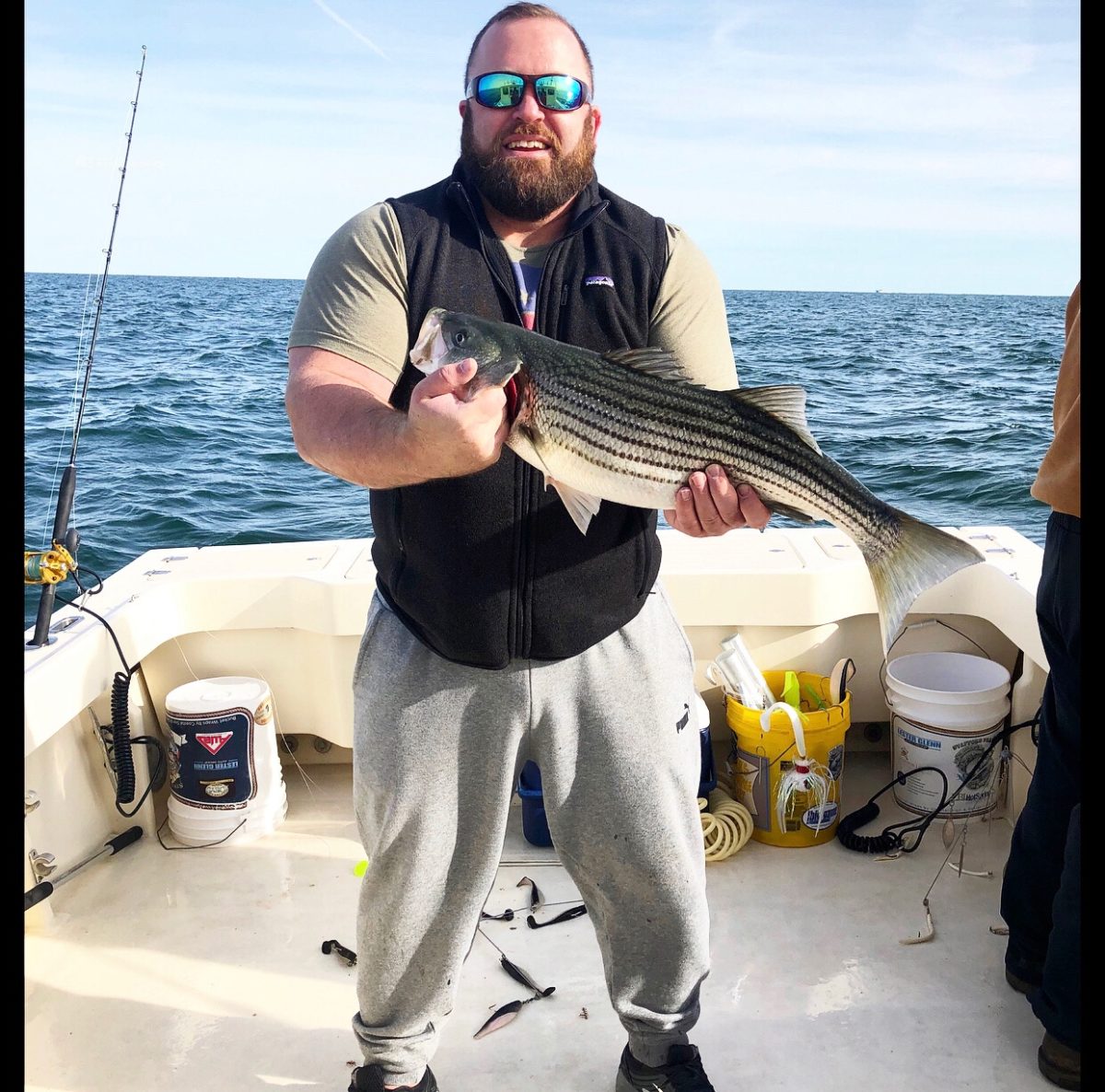 A man holding a striped fish on top of a boat.