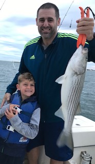 A man and boy holding a striped fish.